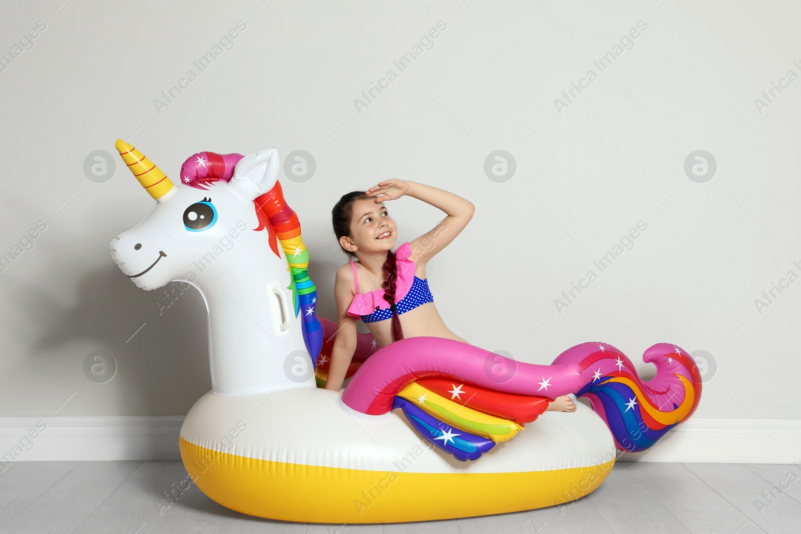 Photo of Cute little girl on bright inflatable ring near light wall