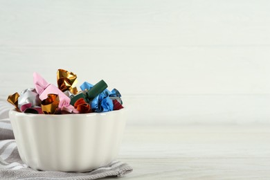 Photo of Candies in colorful wrappers on white wooden table, space for text