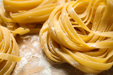 Photo of Tagliatelle pasta on wooden board, closeup view