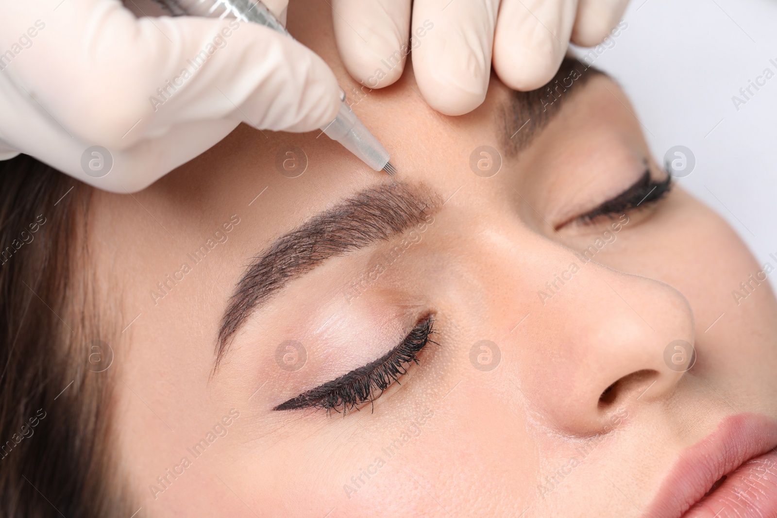 Photo of Young woman during procedure of permanent eyebrow makeup, closeup