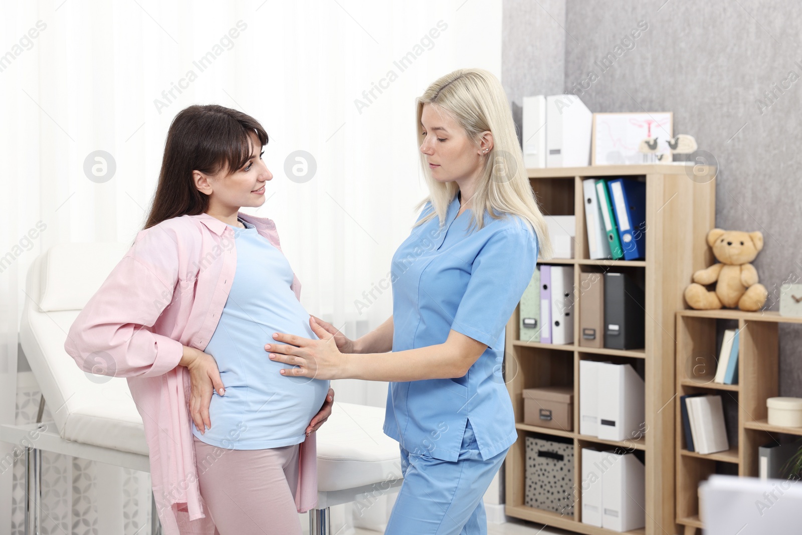 Photo of Pregnancy checkup. Doctor examining patient's tummy in clinic