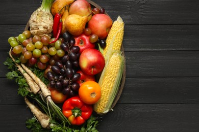 Photo of Different fresh vegetables and fruits on black wooden table, top view with space for text. Farmer harvesting
