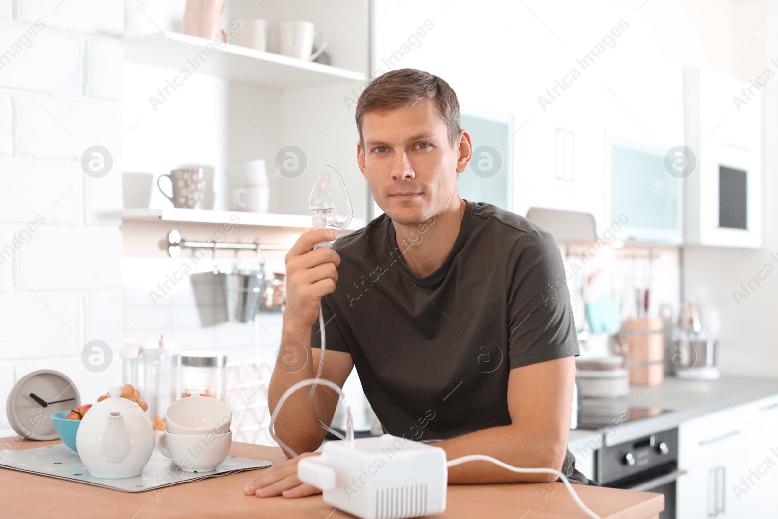 Photo of Man using asthma machine at table in kitchen