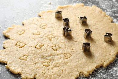 Making shortcrust pastry. Raw dough and cookie cutters on grey table