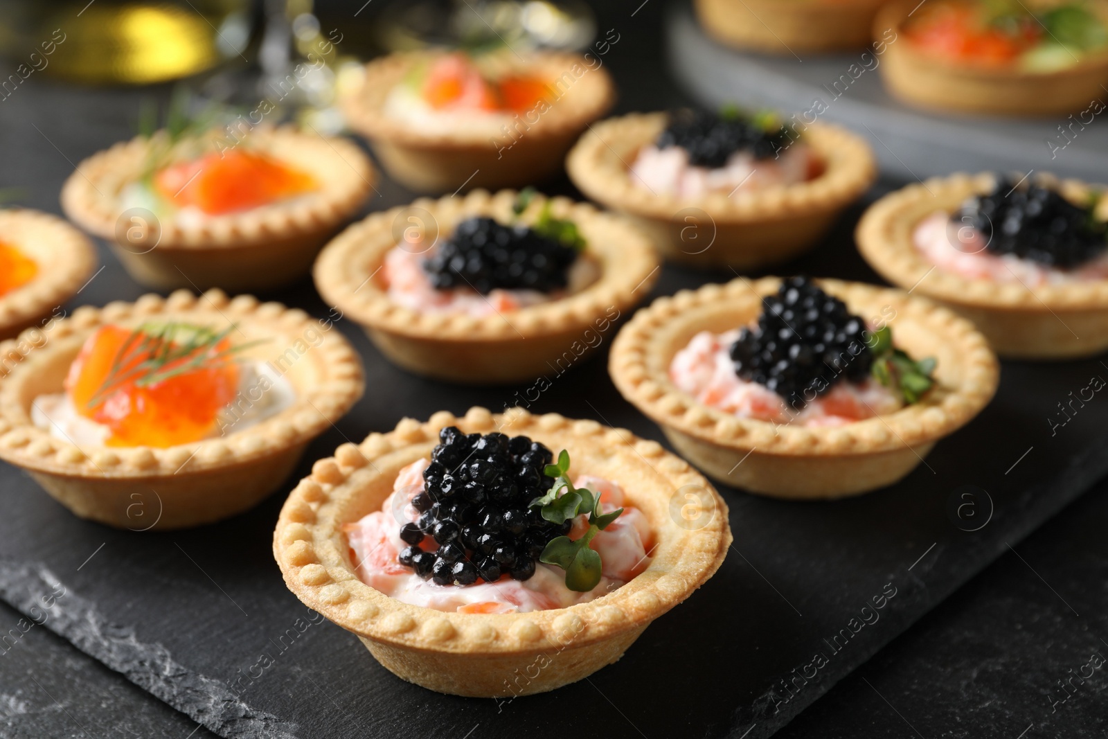 Photo of Delicious canapes with salmon and caviar on black table, closeup