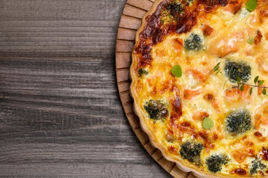 Photo of Delicious homemade quiche with salmon and broccoli on wooden table, top view. Space for text