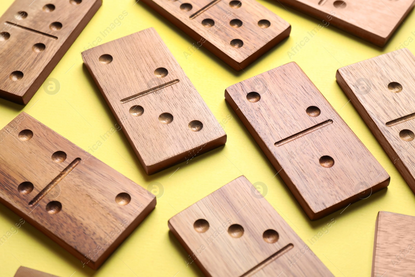 Photo of Wooden domino tiles on yellow background, closeup