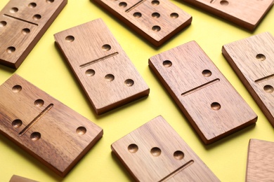 Photo of Wooden domino tiles on yellow background, closeup