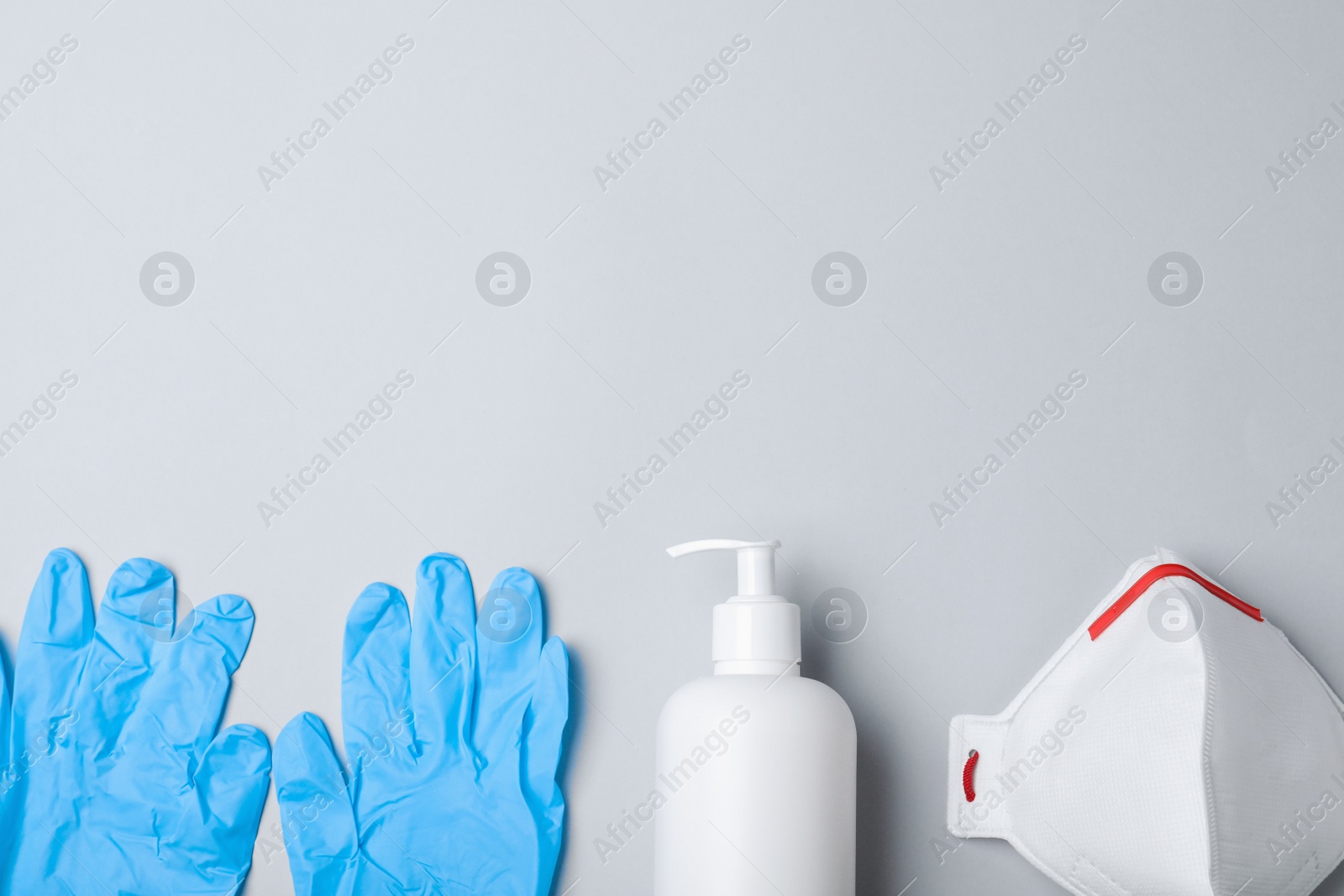 Photo of Medical gloves, respiratory mask and hand sanitizer on grey background, flat lay. Space for text