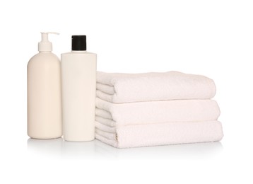 Folded soft terry towels with cosmetic products on white background