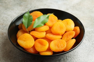 Photo of Plate of tasty apricots on grey table. Dried fruits