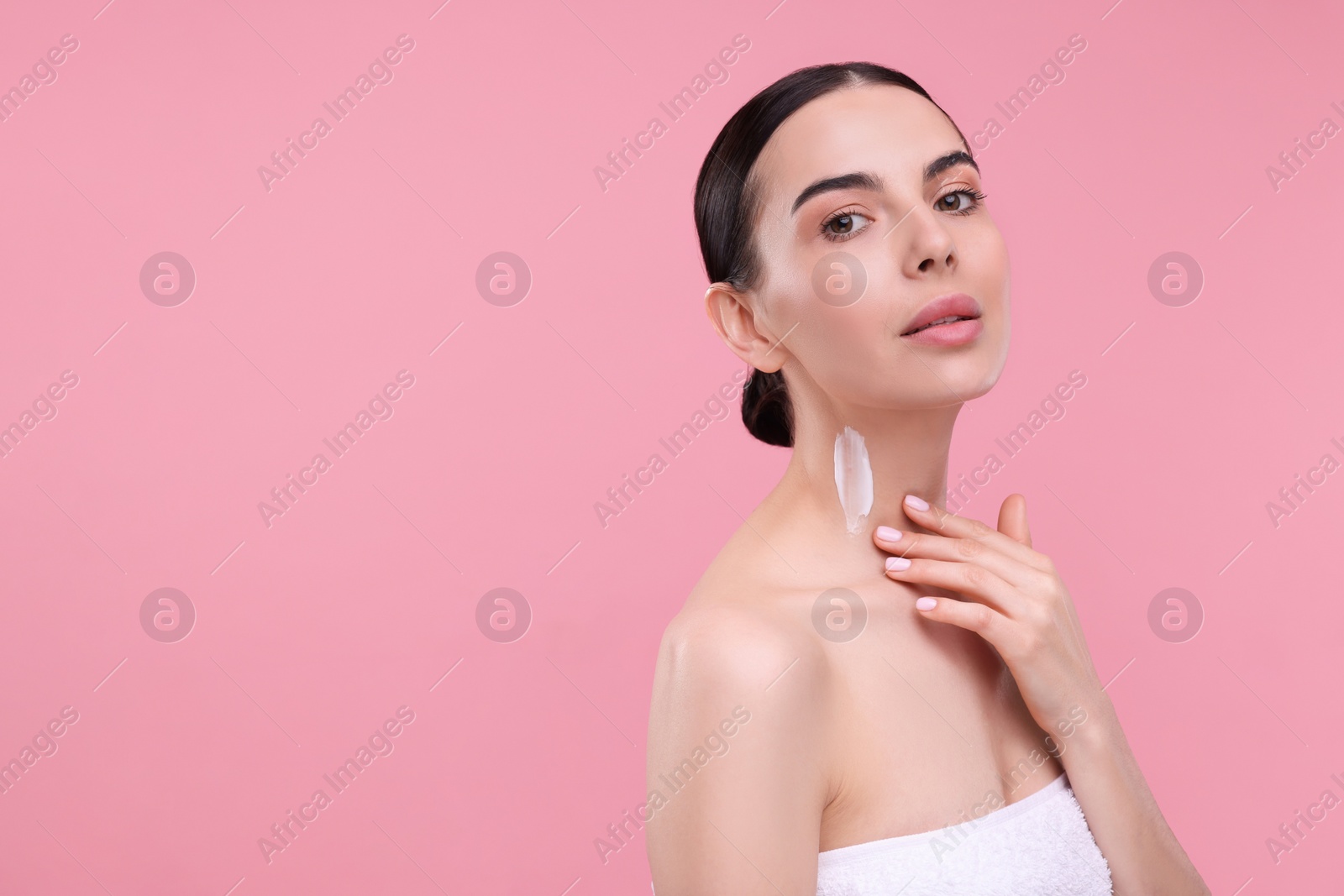 Photo of Beautiful woman with smear of body cream on her neck against pink background, space for text