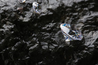 Different shiny diamonds on wet stone surface. Space for text