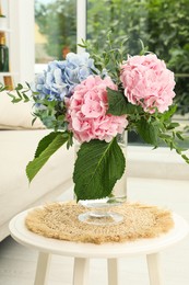 Photo of Bouquet with beautiful hortensia flowers on table in living room