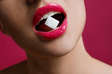 Photo of Woman with beautiful lips eating sugar cube on pink background, closeup
