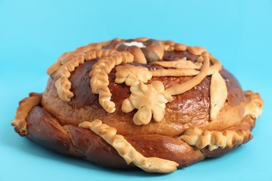 Photo of Fresh korovai on light blue background, closeup. Ukrainian bread and salt welcoming tradition