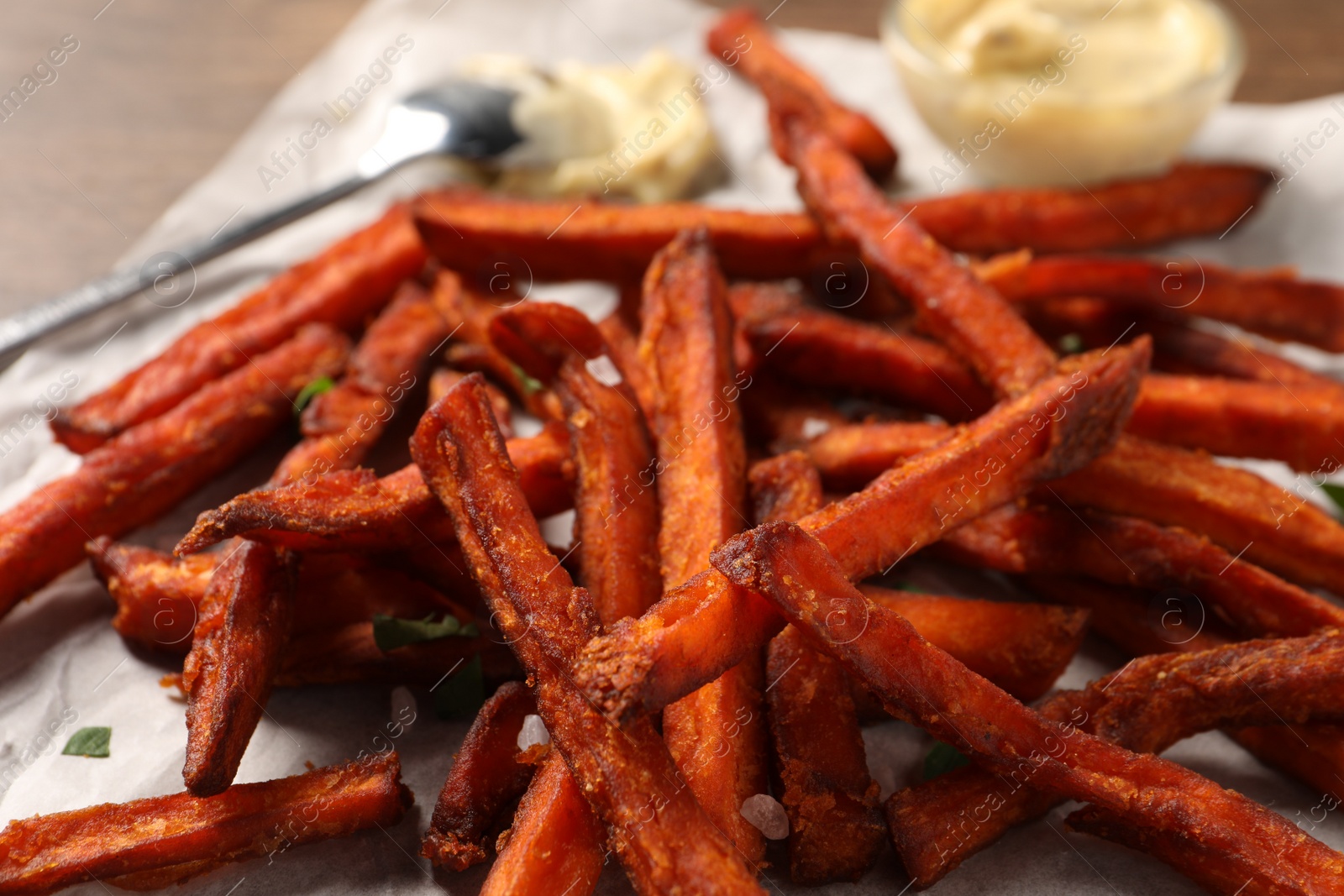 Photo of Delicious sweet potato fries on parchment paper, closeup