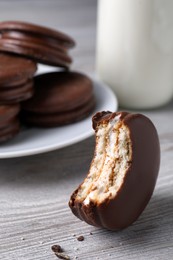 Photo of Tasty bitten choco pie on white wooden table, closeup view