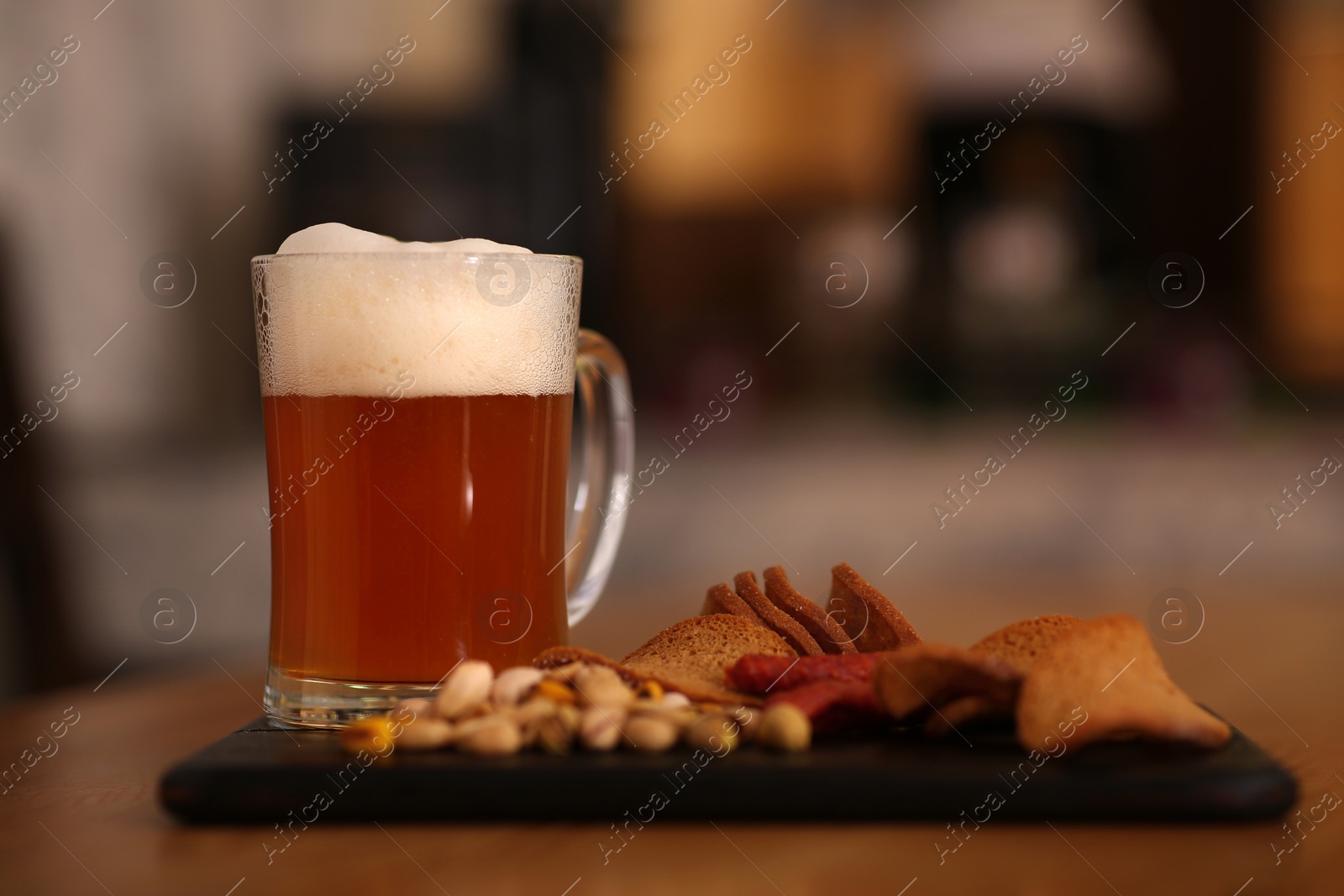 Photo of Pint of cold tasty beer served with snacks on table