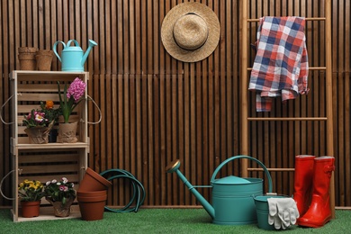 Composition with different gardening tools on artificial grass at wooden wall. Space for text