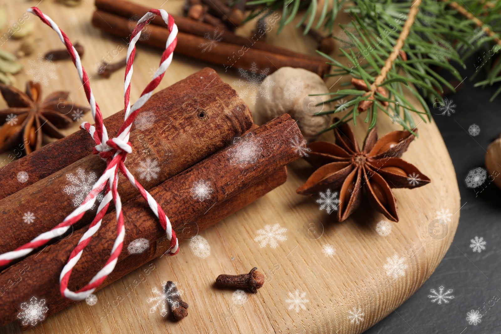 Image of Different spices and fir tree branches on black table, closeup. Cinnamon, cloves, anise, cardamom, nutmeg