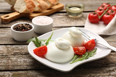 Delicious burrata cheese with arugula and tomato on wooden table