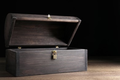 Empty treasure chest on wooden table against black background