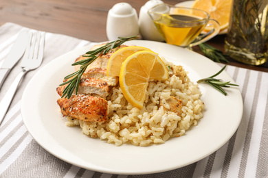 Photo of Delicious chicken risotto with lemon slices on table