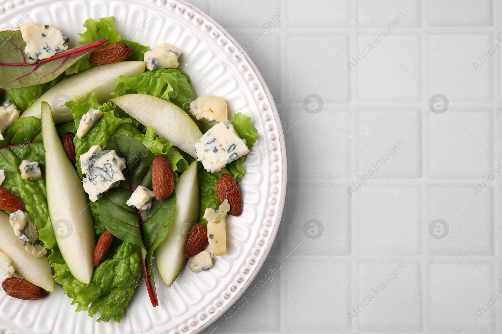 Photo of Delicious pear salad on white tiled table, top view. Space for text