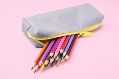 Photo of Many colorful pencils in pencil case on pink background, closeup