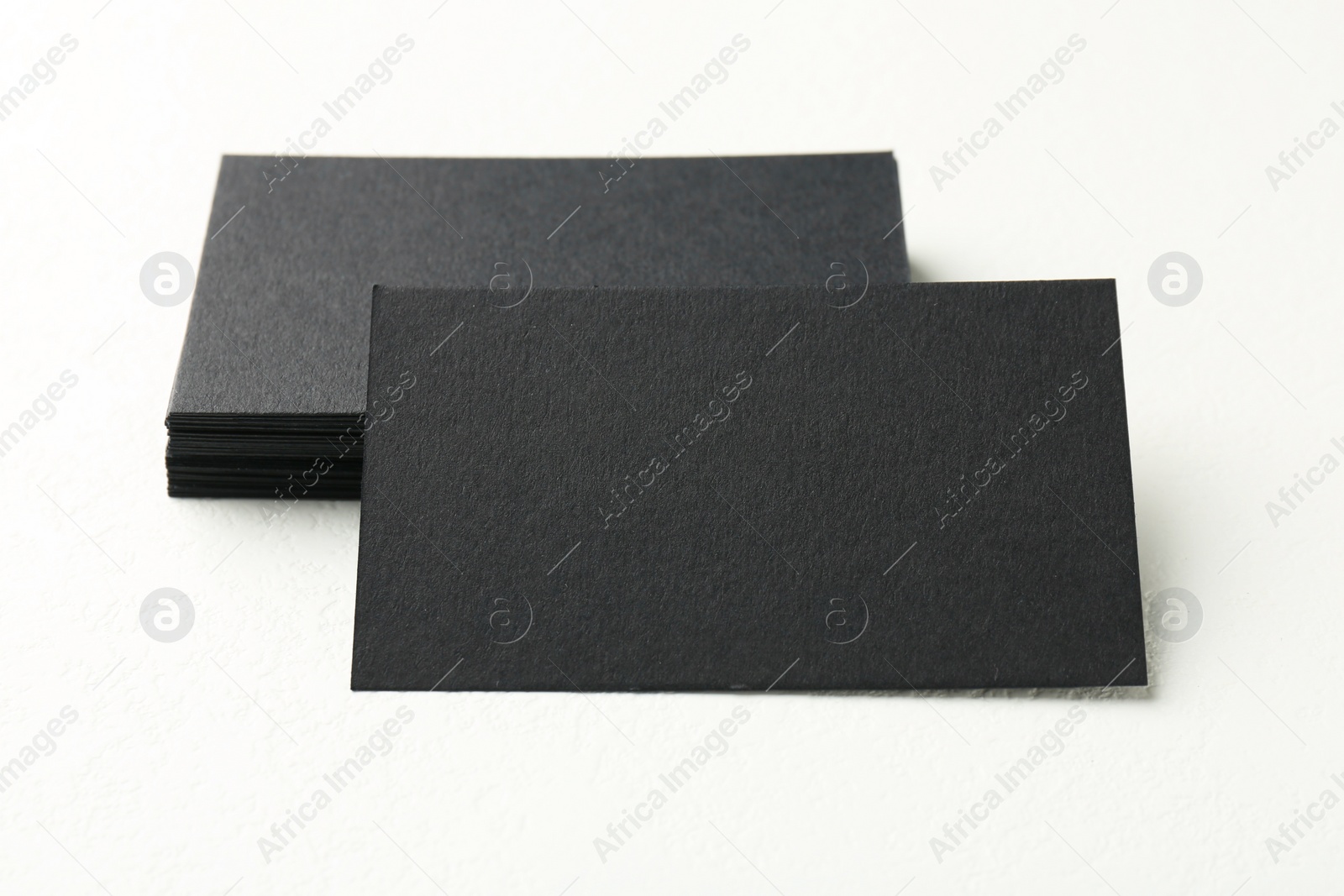 Photo of Blank black business cards on white table, closeup