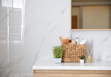Photo of Different toiletries and green plants on countertop in bathroom