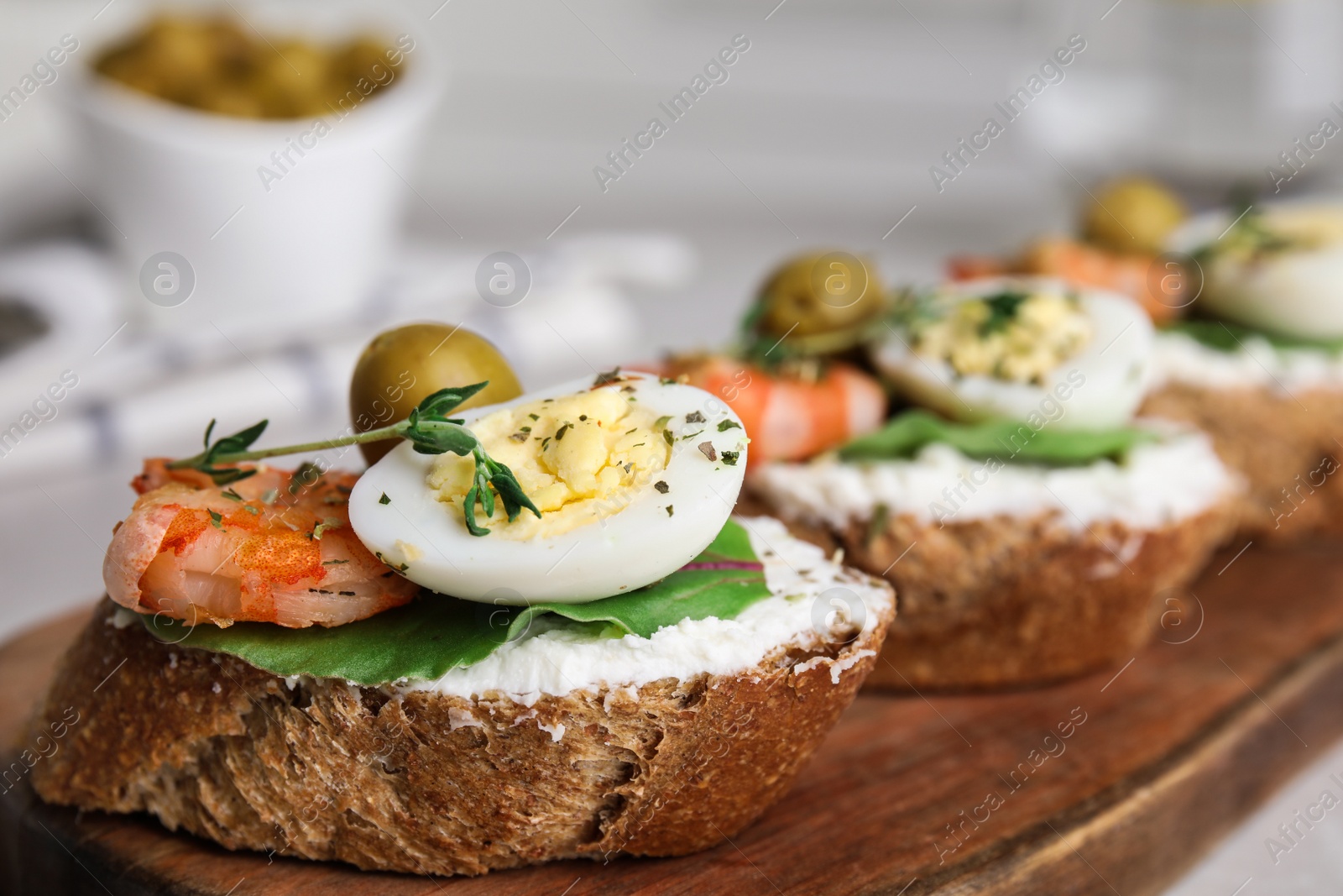 Photo of Cutting board of delicious bruschettas with shrimps on table, closeup