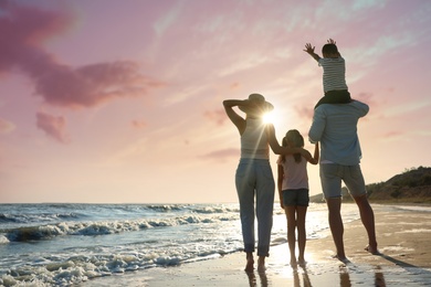 Photo of Family on sandy beach near sea, back view