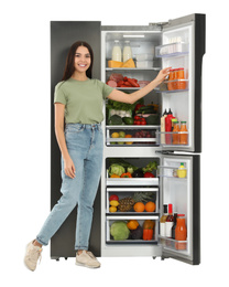 Young woman taking juice from refrigerator on white background