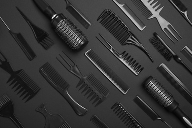 Photo of Flat lay composition with modern hair combs and brushes on black background