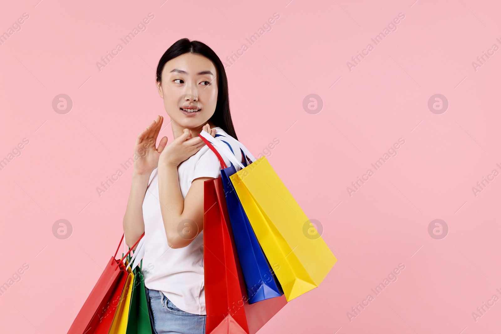 Photo of Smiling woman with shopping bags on pink background. Space for text