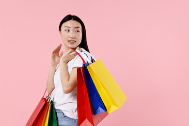 Photo of Smiling woman with shopping bags on pink background. Space for text