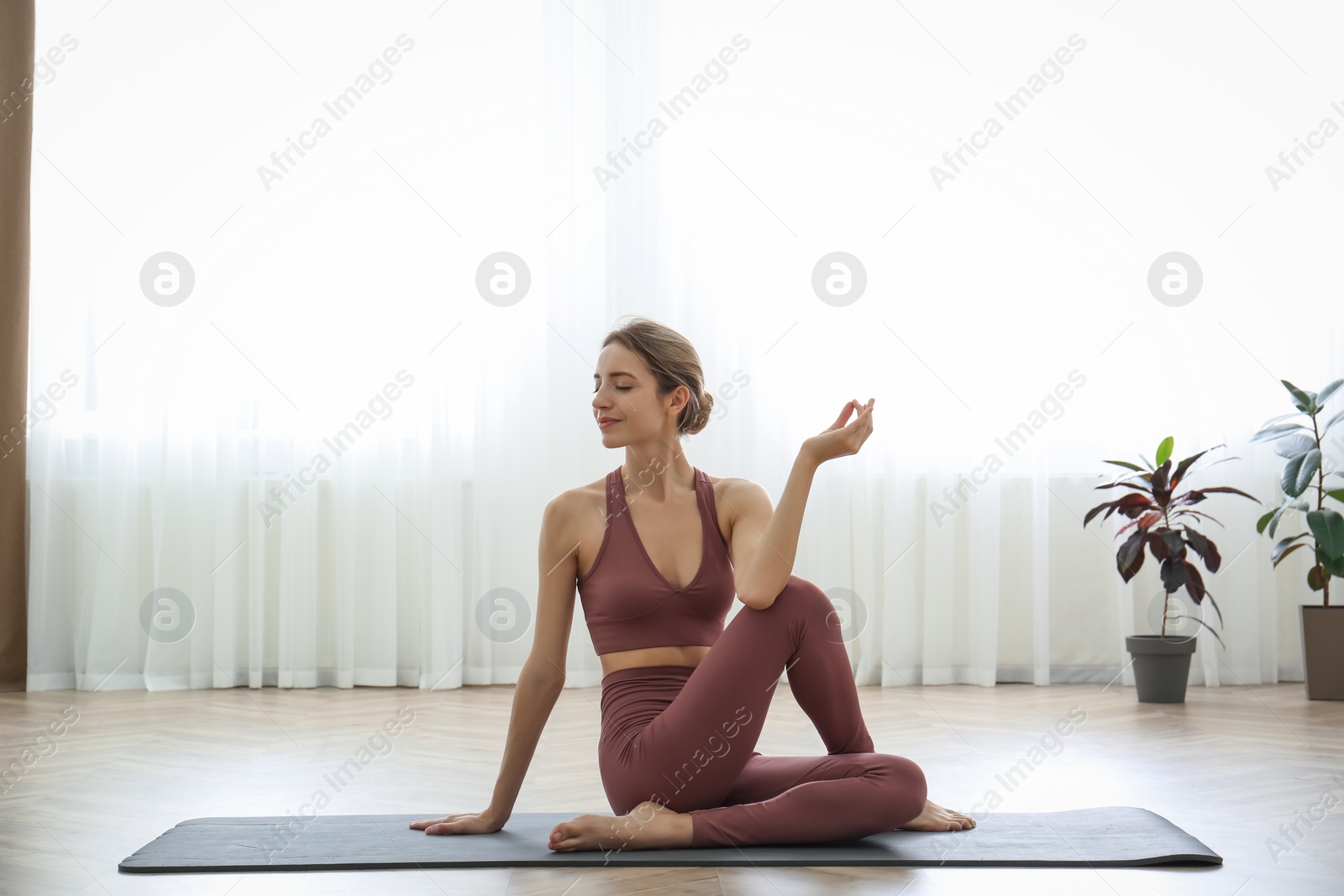 Photo of Young woman practicing half lord of fishes asana in yoga studio. Ardha Matsyendrasana pose