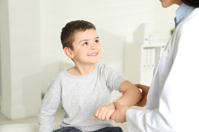 Photo of Professional orthopedist examining little patient's arm  in clinic