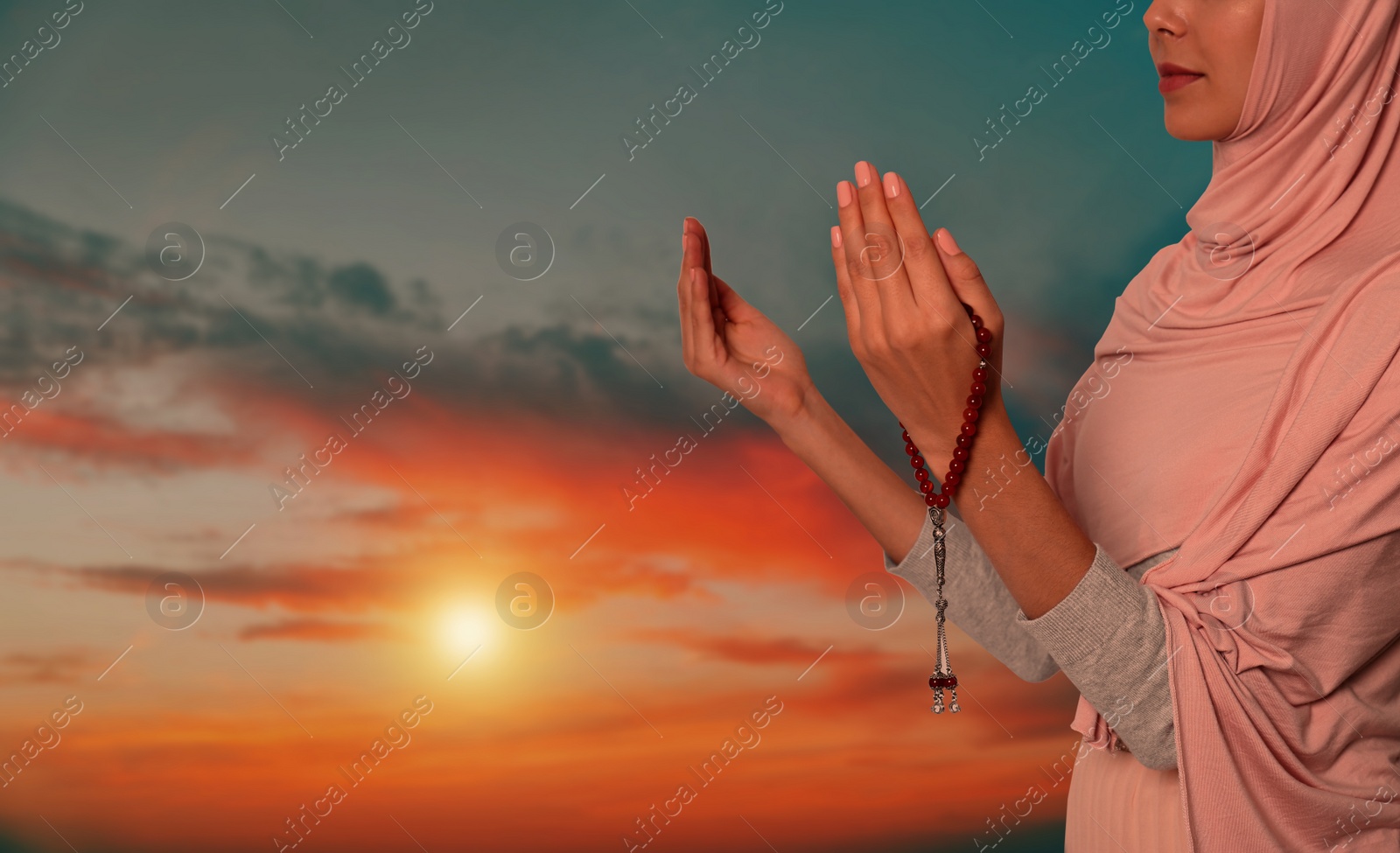 Image of Muslim woman praying outdoors at sunset, closeup