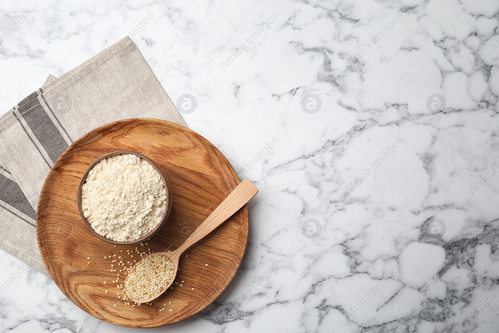 Photo of Bowl with sesame flour and seeds in spoon on marble background