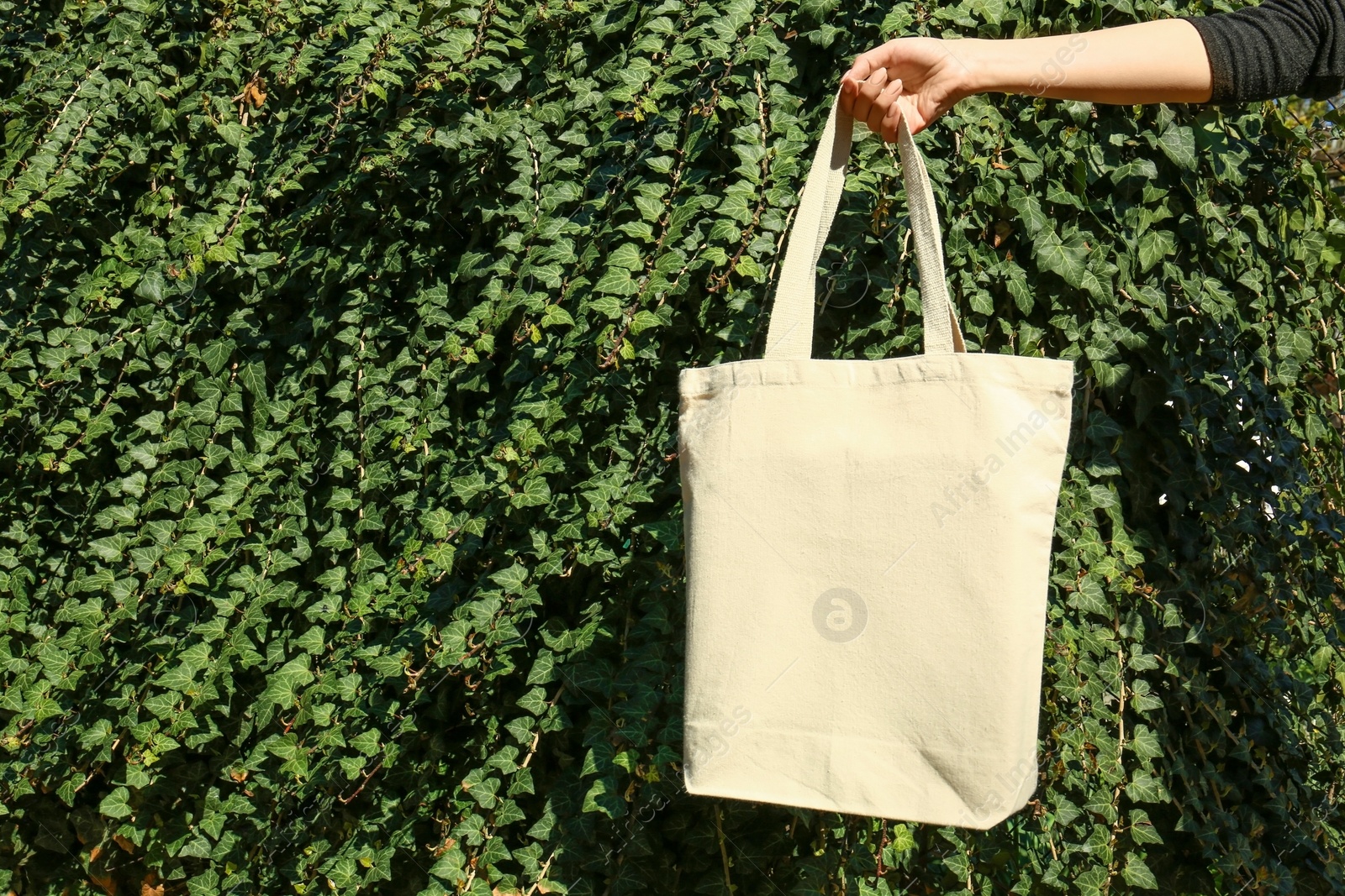 Photo of Woman holding eco bag outdoors, closeup. Mockup for design