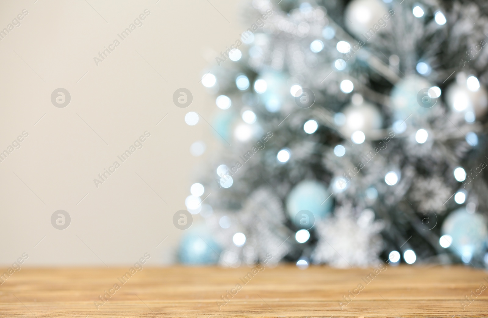 Photo of Empty wooden table and blurred fir tree with Christmas lights on background, bokeh effect. Space for design