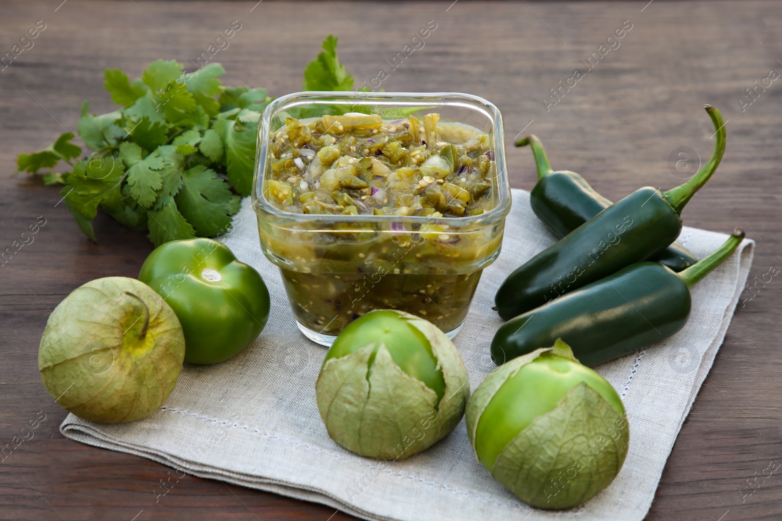 Photo of Tasty salsa sauce and ingredients on wooden table