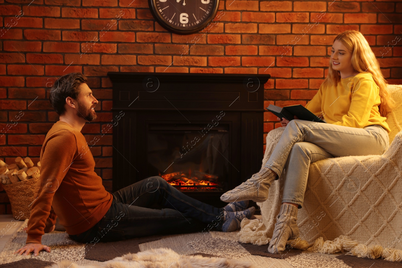 Photo of Lovely couple spending time together near fireplace indoors