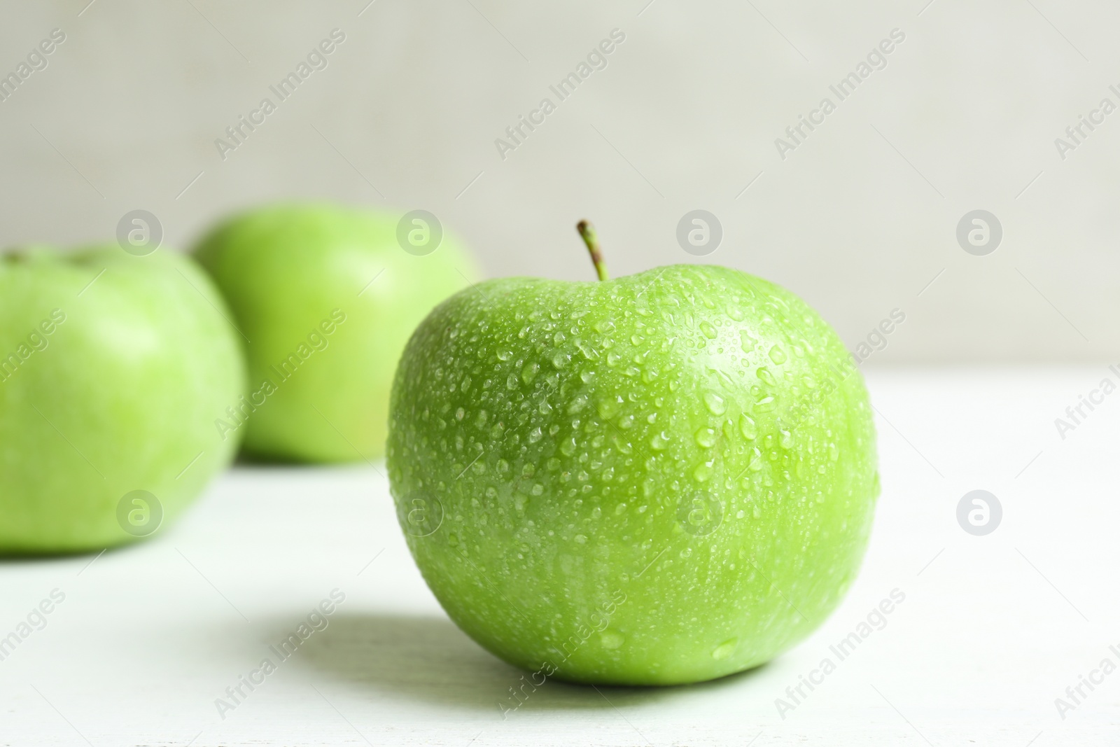 Photo of Fresh green apple with water drops on white table