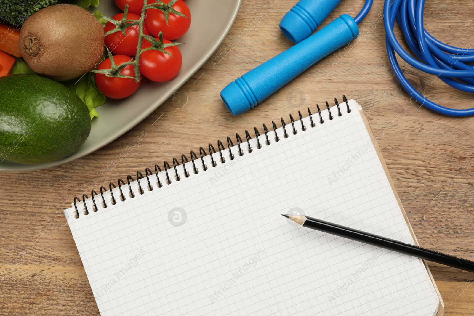 Photo of Weight loss concept. Notebook, skipping rope and different products on wooden table, flat lay