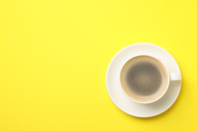 Aromatic coffee in cup on yellow background, top view. Space for text