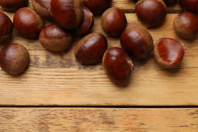 Photo of Sweet fresh edible chestnuts on wooden table, top view. Space for text